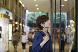 A woman in a shopping mall looking at a shop window display.